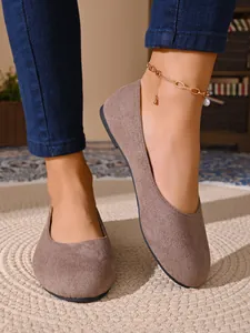 Primo piano di ballerine da donna in camoscio tortora con design a punta tonda.