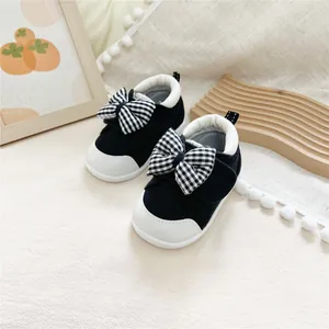 Detail view of black and white baby walking shoes with charming plaid bow accents.
