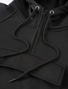 Close-up of black drawstring hoodie with half-zip detail and premium fabric texture