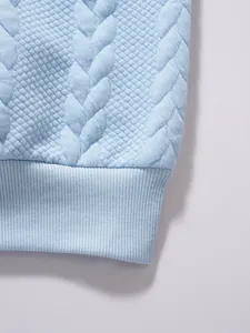 Macro detail of light blue men's polo shirt showing jacquard knit and ribbed hem