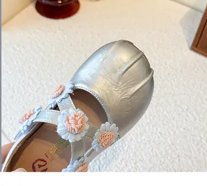 Detailaufnahme der silbernen Mary Jane Schuhe für Mädchen mit dekorativen Blumen.