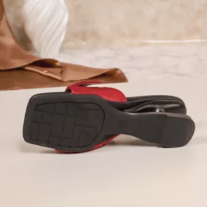 Dettaglio di sabot rossi a punta quadrata con un esclusivo tacco geometrico nero moderno