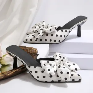 Détail du nœud surdimensionné et du motif à pois sur cette mule en satin élégante