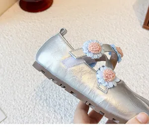 Detail der silbernen Mary Jane Mädchenschuhe mit hellblauen gewebten Blumenornamenten