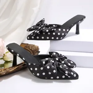 Gros plan d'élégantes mules à pois noir et blanc avec bout pointu et nœud décoratif