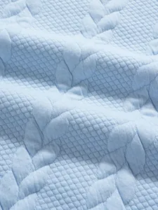 Close-up of light blue men's polo shirt featuring leaf jacquard and waffle texture fabric