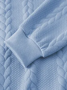 Macro detail of blue jacquard knit polo shirt showing ribbed cuff and textured fabric