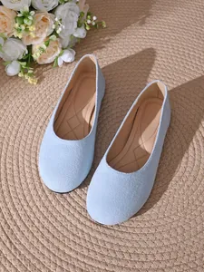 Dettaglio delle ballerine in pelle scamosciata azzurra a punta tonda su tappeto di paglia