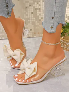 Elegant transparent high heel mules with oversized cream bow and wine glass heel design
