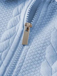 Close-up detail showing the silver metallic zipper on light blue jacquard knit polo shirt