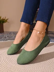 Dettaglio di ballerine da donna in camoscio verde con punta tonda e cavigliera dorata.