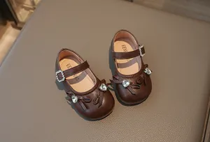 Detailansicht brauner Mädchen Mary Jane Schuhe mit Strassherz und Schleifenakzenten.