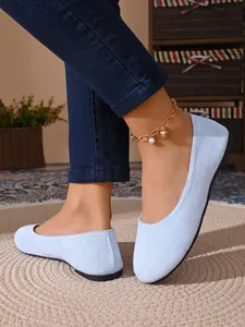 Dettaglio di ballerine in camoscio azzurro a punta tonda con jeans