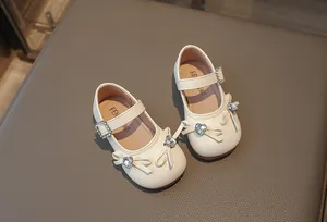 Detailansicht der eleganten cremefarbenen Mädchen-Mary Janes mit einer glitzernden Herzschleife