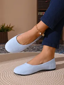 Primo piano di ballerine azzurre in camoscio a punta tonda che mostrano la texture.