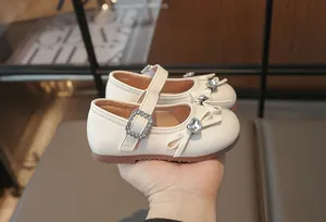 Nahaufnahme von weißen Mädchenschuhen mit Strassschleife und einem glitzerndem Herz