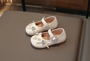 Detailansicht eleganter cremefarbener Mädchen-Mary-Janes mit Strassschleife und Herzschnalle