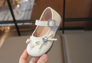 Detailaufnahme von cremefarbenen Mädchen-Ballerinas mit Strass-Herzschleife und Schnalle