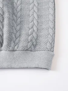 Macro view of the grey cable-knit jacquard fabric texture and ribbed hem detail.