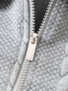 Close-up detail of silver zipper and diamond jacquard texture on grey men's polo shirt