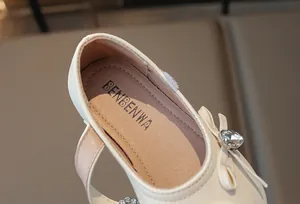 Nahaufnahme von beigefarbenem Prinzessinnenschuh mit Strassschleife und Sohlendetail