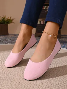 Primo piano di scarpe basse in camoscio rosa con cavigliera in oro e perle