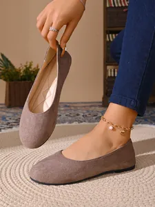 Dettaglio di ballerine in camoscio tortora minimaliste in un accogliente ambiente interno
