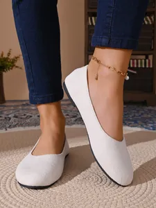 Primo piano dettagliato di eleganti ballerine in camoscio bianco da donna su tappeto