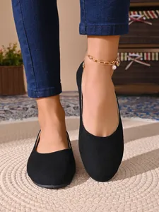 Dettaglio di ballerine in camoscio nero con punta tonda indossate con jeans