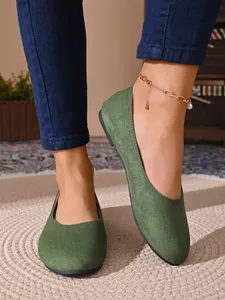 Dettaglio di eleganti ballerine in finto camoscio verde con punta tonda su un tappeto