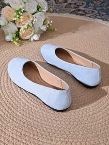 Dettaglio di scarpe basse in camoscio azzurro con punta tonda su tappeto intrecciato