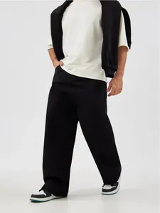 Detail of men's loose black straight jeans styled with a casual white t-shirt
