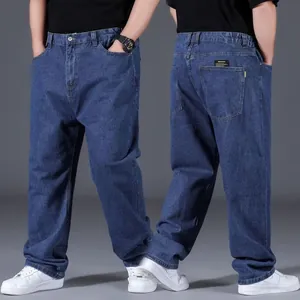 Detailed view of men's loose oversize straight-leg jeans in dark blue denim fabric