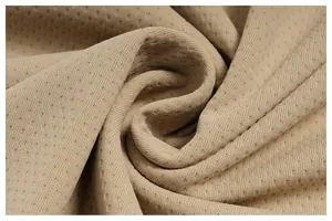 Detailed macro view of the breathable perforated fabric texture for a beige sports T-shirt