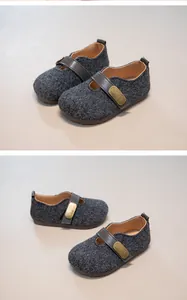Detailed view of grey wool texture and leather strap on retro children's shoes.