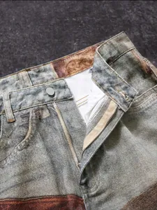 Detalle de vaqueros con estampado 3D teñidos en barro con cremallera y botón