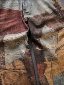 Vista de detalle macro de vaqueros patchwork teñidos con barro y efectos rotos.