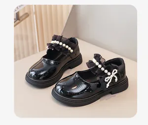 Dettaglio scarpe in vernice nera per bambine con elegante fiocco di perle e pizzo