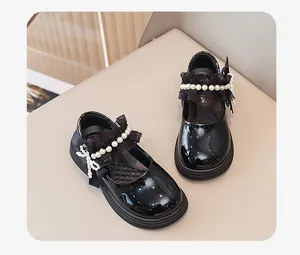 Dettaglio di eleganti scarpe Mary Jane nere in vernice per bambina con perle e pizzo