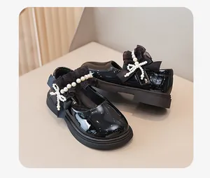 Dettaglio di scarpe da principessa in vernice nera con perle e fiocco di pizzo