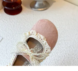 Vue détaillée de chaussure de princesse en daim rose avec dentelle, nœud et perles nacrées.
