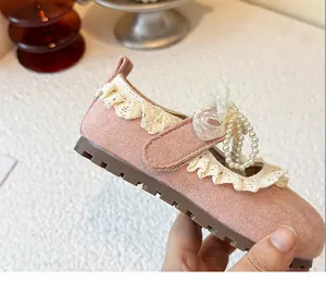 Détail d'une chaussure de princesse rose pour fille avec dentelle et nœud de perles.