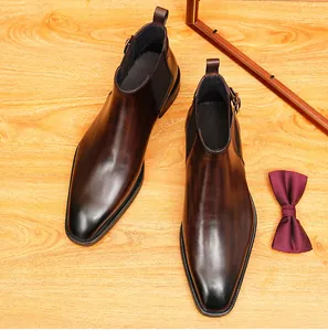 Vue de dessus de bottines Chelsea en cuir marron pour hommes avec un nœud papillon.