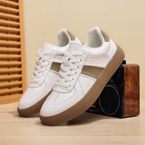 Detailed close-up view of white leather GAT sneakers featuring brown gum soles and white laces