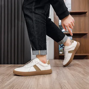 Stylish men's white leather GAT sneakers with gum sole shown on foot in a room.