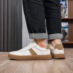 Detail shot of white and brown men's GAT style leather sneakers being worn on floor