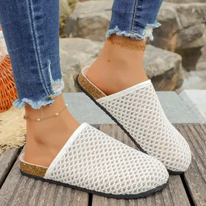 Detail shot of white woven mesh clog slippers with cork sole on a wooden deck