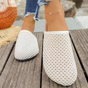 Detailed close-up view of stylish white woven mesh flat mules for summer vacation