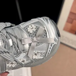 Primer plano de zapatilla deportiva plateada para niña con lazo y flores