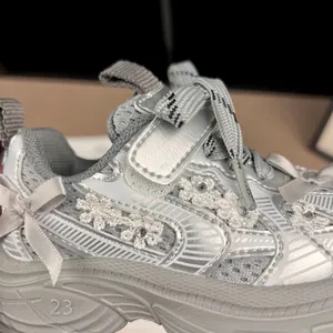 Primer plano de zapatillas plateadas para niña con flores de encaje y detalles de lazos